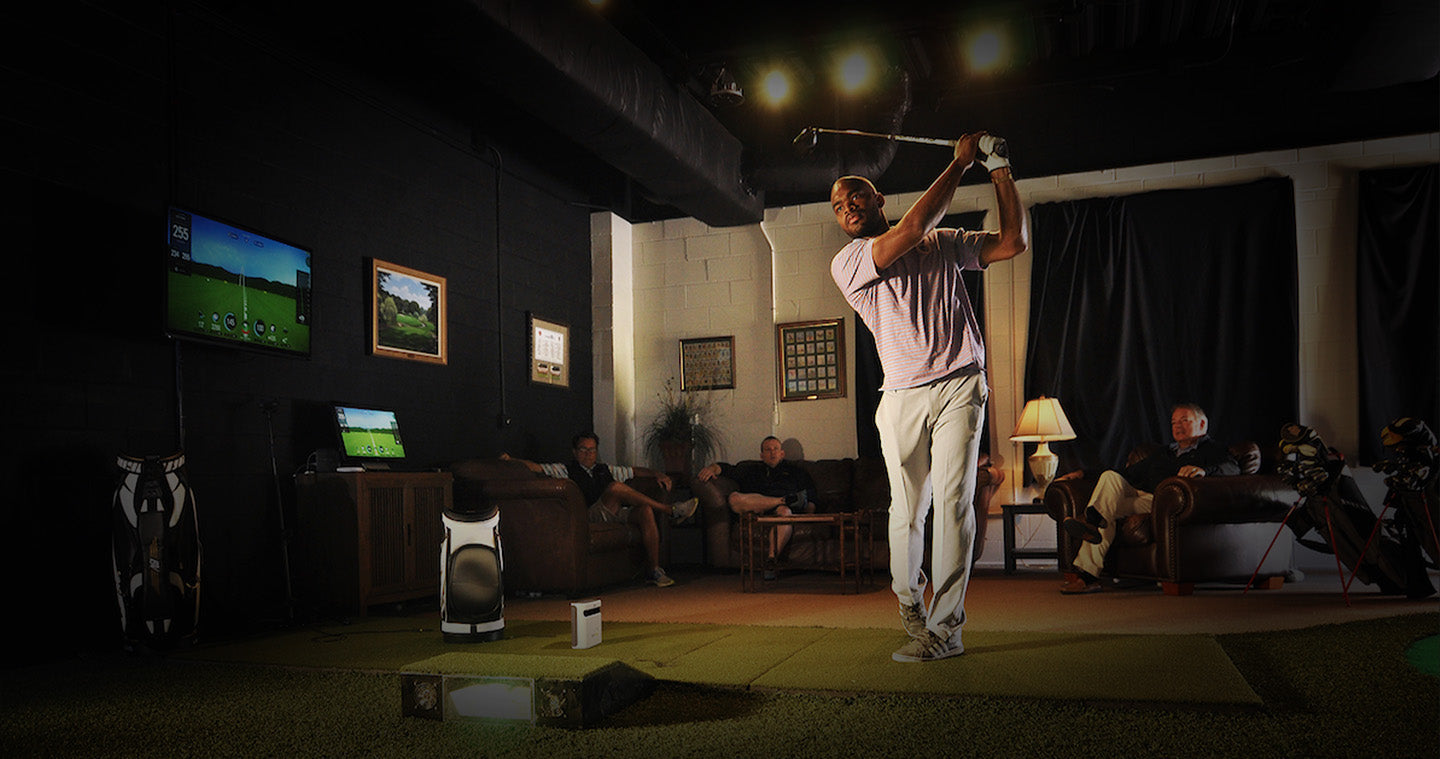 Guy playing golf indoors with friends on SKYTRAK golf simulator