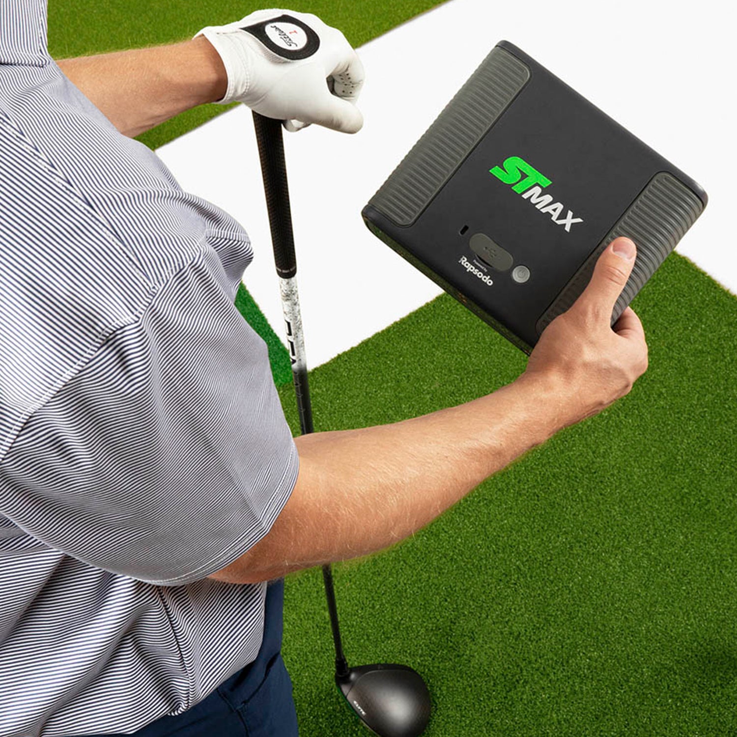 Person holding SKYTRAK ST MAX launch monitor on hitting mat holding driver in the other hand