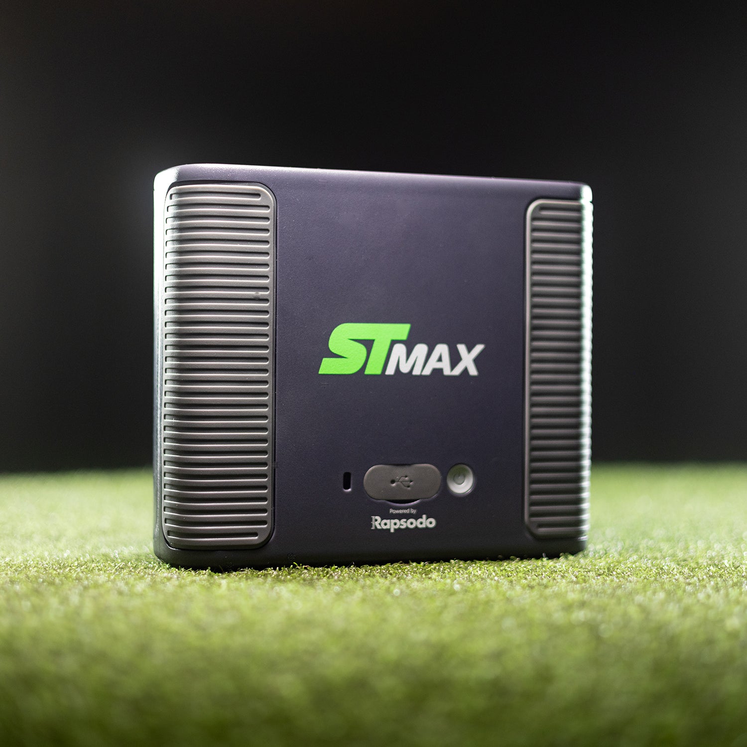 ST Max device on a grassy surface with a dark background