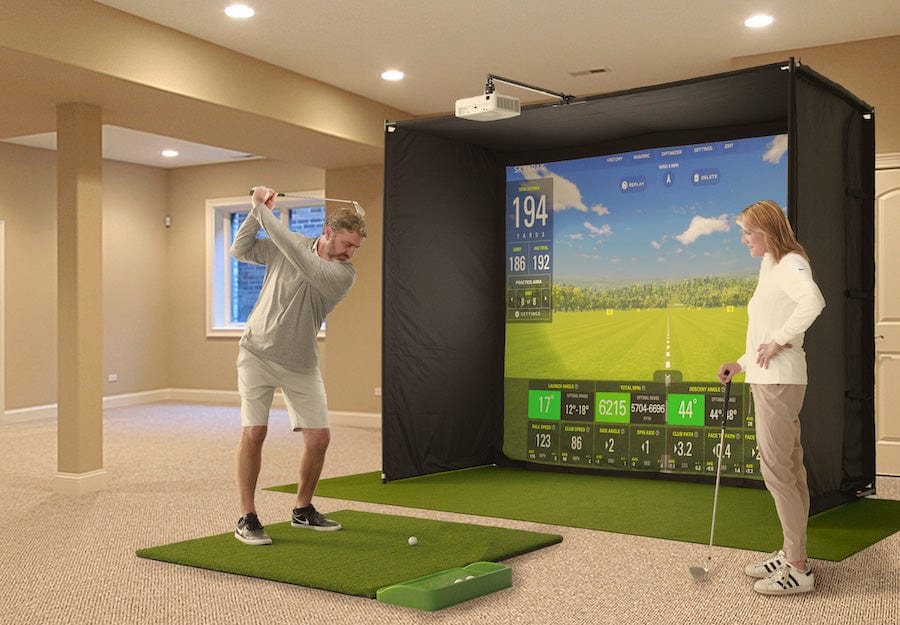 Man and woman using the SkyTrak golf simulator studio in their basement