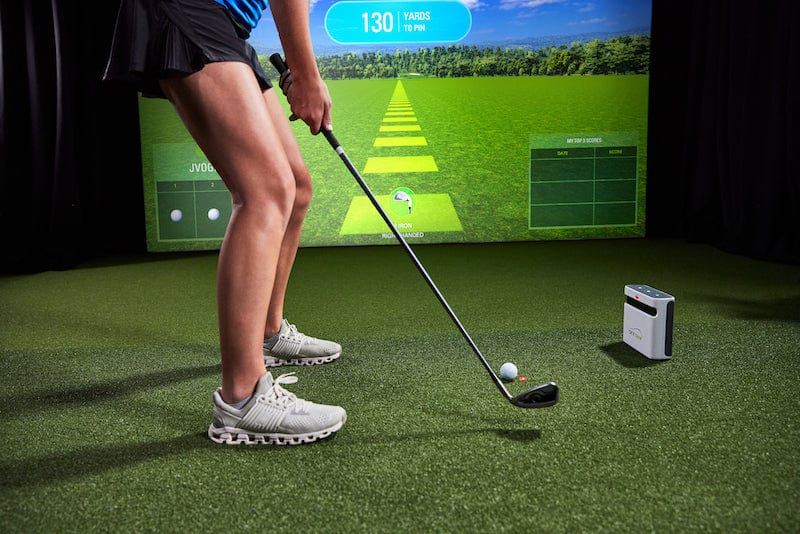 Woman hitting on an indoor golf simulator powered by SKYTRAK+ launch monitor