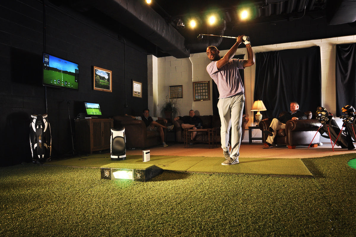 man playing on a golf simulator with friends and the SKYTRAK plus launch monitor