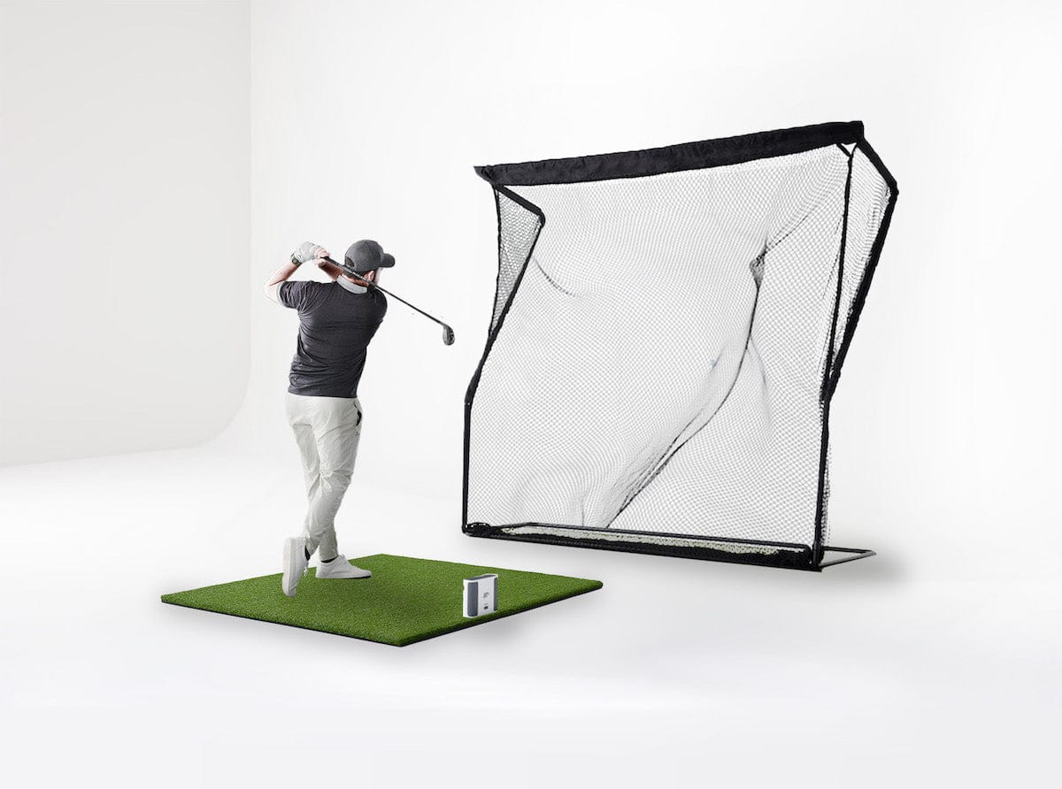 Man playing golf simulation with SKYTRAK plus launch monitor and mat and return net golf accessories
