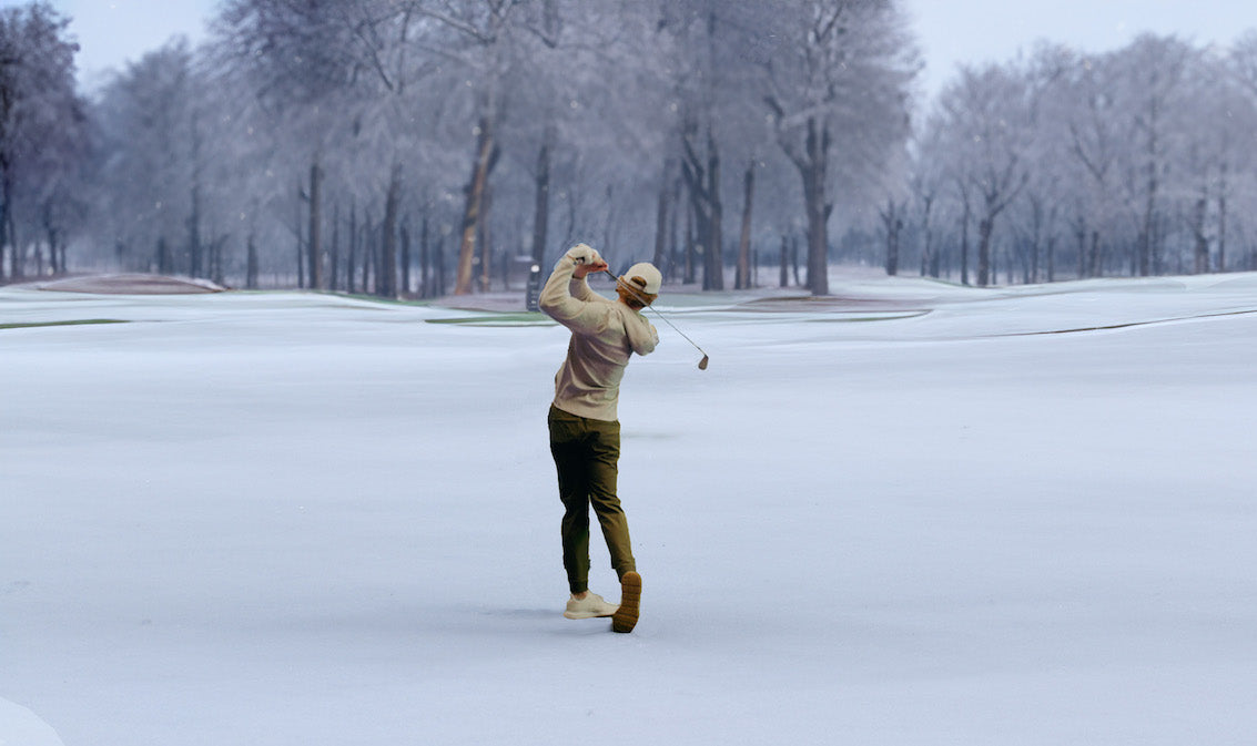 man playing golf outside in the snow instead of on his home DIY golf simulator