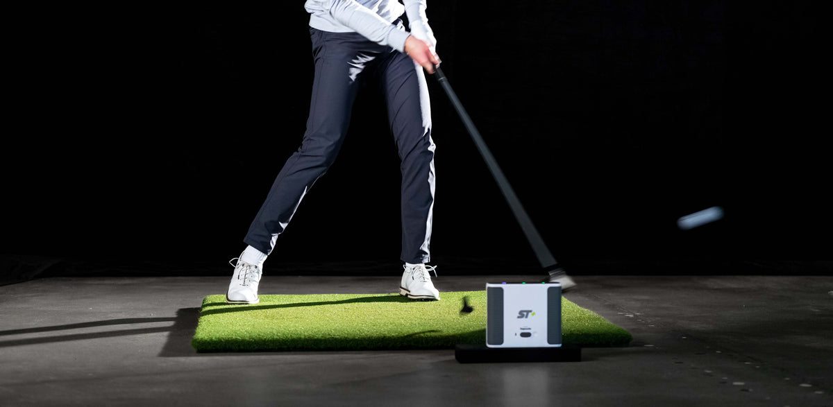 Guy hitting a golf ball on a mat with SkyTrak+ Launch Monitor